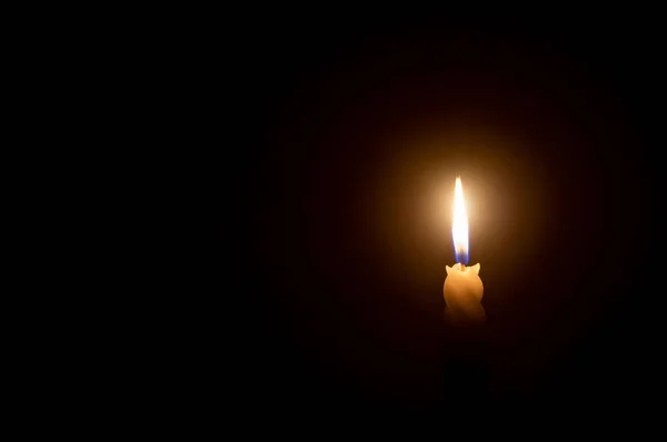 単一の燃焼キャンドル炎や光は コピースペースとクリスマス 葬儀や記念サービスのための教会でテーブルの上に黒または暗い背景に白いスパイラルキャンドルに輝いています — ストック写真