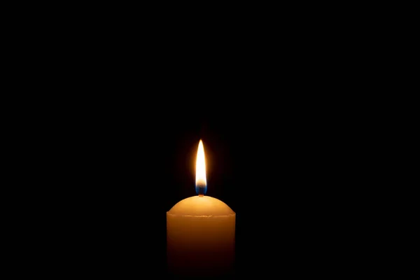 単一の燃えるろうそくの炎かライトはコピースペースが付いている教会のテーブルのテーブルの黒いまたは暗い背景の大きい白いろうそくで輝いています — ストック写真