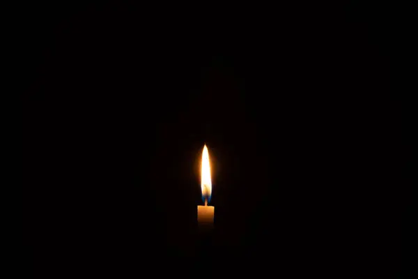 単一の燃えるろうそくの炎かライトはコピースペースが付いている教会のテーブルのテーブルの黒いまたは暗い背景の小さな白いろうそくで輝いています — ストック写真