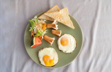 Kahvaltının koyu yeşil tabakla üst tarafındaki fotoğrafı beyaz masa örtüleriyle birlikte masadadır. 