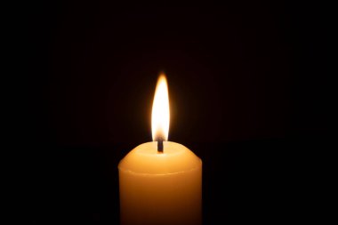 Büyük beyaz bir mumun üzerinde parlayan tek bir mum ya da ışık kilisedeki kırmızı ya da koyu arkaplanda Noel, cenaze ya da anma töreni için izole edilir.