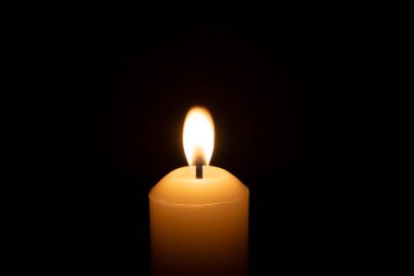 Büyük beyaz bir mumun üzerinde parlayan tek bir mum ya da ışık kilisedeki kırmızı ya da koyu arkaplanda Noel, cenaze ya da anma töreni için izole edilir.