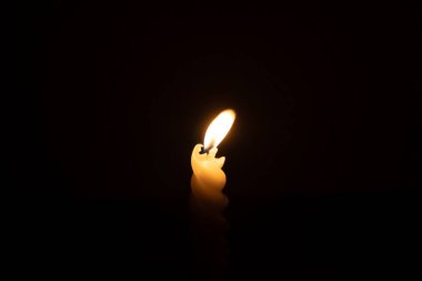 Yanan tek bir mum ya da ışık, kilisede Noel, cenaze ya da anma töreninde fotokopi alanı olan siyah ya da koyu arkaplanda sarmal beyaz bir mum üzerinde parlıyor.