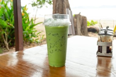 Soğuk kibrit sütlü sütlü, şeffaf plastik bardaklı soğuk bir içecek deniz kenarındaki kafenin masasında..