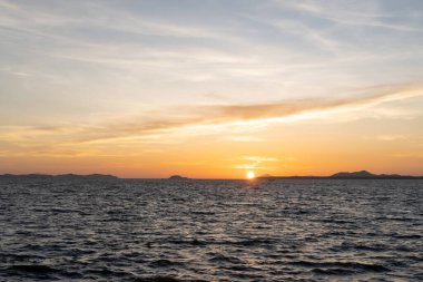 Güneşin doğuşu ve doğuşu doğal karaltı dokusu olarak kullanılan denizde çekilirken önü ve güzel sabah veya akşam mavi ve turuncu gökyüzü bulutlu.