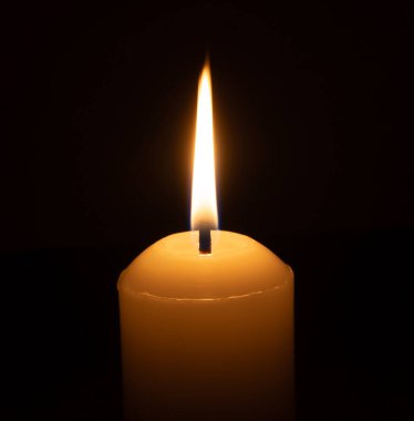 Büyük beyaz bir mumun üzerinde parlayan tek bir mum ya da ışık kilisedeki siyah ya da koyu arkaplanda Noel, cenaze ya da anma töreni için izole edilir.