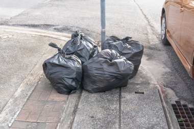 Şehir merkezinde, patikadaki çöplükte siyah çöp torbasında çöp toplandı..