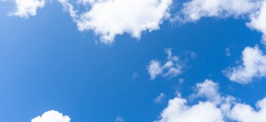 Güneşli bir günde sabah veya akşam tüylü beyaz bulutların tuhaf şekilli güzel mavi gökyüzünün alçak açısı dekoratif sanat eserlerinde doğal arkaplan dokusu olarak kullanılır..