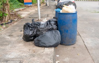 Çöpler siyah çöp torbasında, mavi çöp bidonları ise şehir caddesinin patikasında.. 