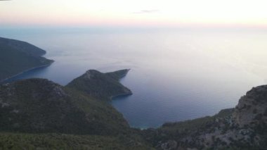 Gökyüzü deniz manzaralı yeşil kayalar mavi denizle çevrili sonsuz deniz gün batımında dağların üzerinden uçarak dünyadaki cennet terk edilmiş lagün. Yüksek kalite 4k görüntü