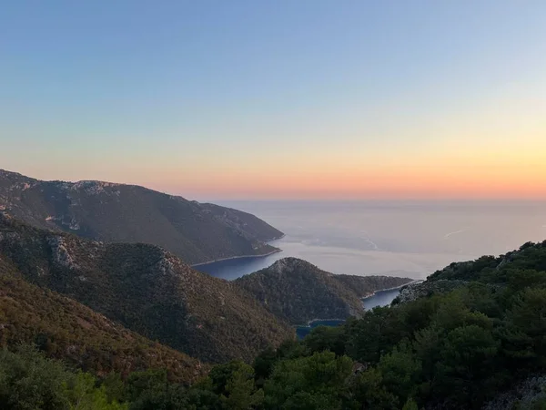 Gün batımında sonsuz gül denizi. Mavi denizle çevrili yeşil kayalar. Günbatımında insan olmadan gölcük. Yüksek kalite fotoğraf