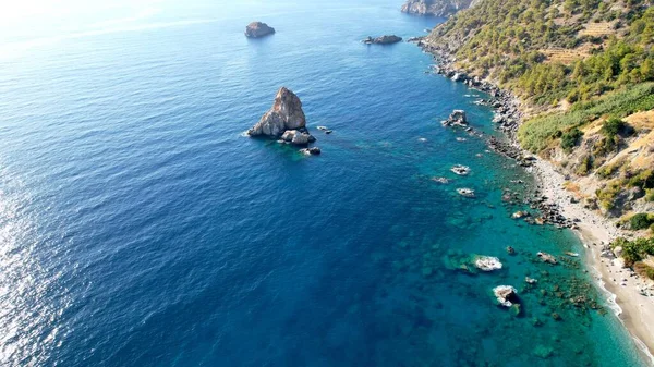 Terk edilmiş bir turkuaz gölün hava fotoğrafında kuş bakışı bir perspektiften bakıldığında, berrak sular, saklı vahaya şaşırtıcı bir dokunuş ekleyen dağınık kayaları ortaya çıkarıyor.