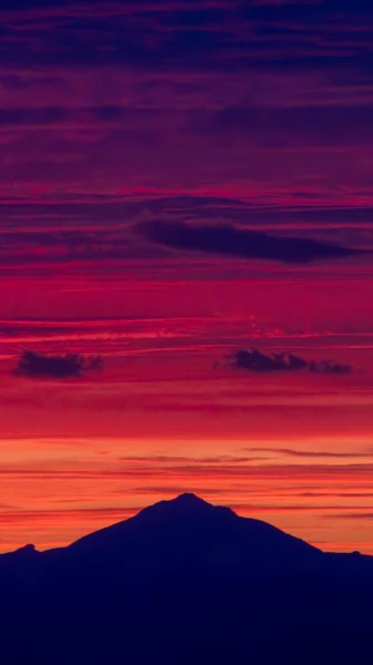Fantastic natural view of mountain silhouette against the backdrop of a mesmerizing sunset sky. Vertical social media banner story background. High quality photo
