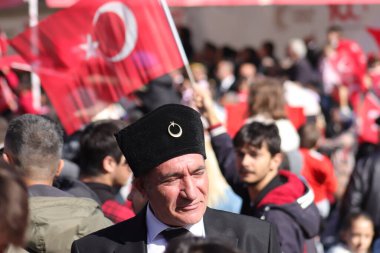 Atatürk 'e benzeyen bir adam, Türk tarihinin bir simgesi olan geleneksel bir fes takarak 29 Ekim kutlamaları sırasında kalabalığa karışıyor. 29 Ekim 2023 - Erzurum, Türkiye .