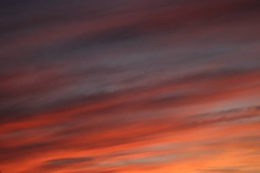 Derin kırmızılar ve portakallarla boyanmış nefes kesici bir günbatımı gökyüzü, sakin ve merak uyandıran dramatik bir zemin. Yüksek kalite fotoğraf