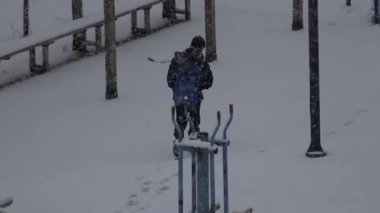 Karda okula yürüyen bir çocuk, arkadan yakalanmış, direnç ve masumiyeti simgeliyor..