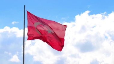 Türk bayrağı açık mavi gökyüzüne karşı dalgalanarak, metni kaplamak için geniş bir alan sağlıyor.