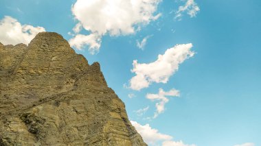 Tortum, Erzurum, Türkiye 'de huzur ve gücü sembolize eden, berrak mavi gökyüzü altındaki kayalık bir dağın görkemli yatay görüntüsü.