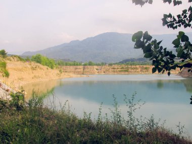 Etrafındaki manzarayı yansıtan sakin bir gölet, huzurlu ve sakin bir atmosfer yaratıyor. Durgun su, doğanın güzelliğini yansıtıyor. Huzur hissi uyandırıyor.