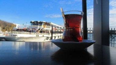 Masada Türk çay bardağı, feribotlar, deniz ve huzurlu bir ufukta huzurlu bir an. Seyahat, rahatlama ve hayatın basit zevklerini yansıtmak için mükemmel..