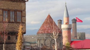 Erzurum 'un İkiz Minare Madrasa' sı, tarihi taş evler ve dalgalanan Türk bayrağı Türkiye 'de tarih, mimari ve kültür mirasının çarpıcı bir karışımını oluşturuyor. 