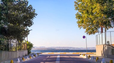 Park yasağı işareti olan, engelleri, istikameti ve hedeflere ulaşmak için zorlukların üstesinden gelme yolculuğunu sembolize eden, ufka doğru giden güneşli bir yol.. 