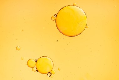 Altın sarısı soyut yağ kabarcıkları ya da yüz serumu arka planı. Petrol ve su baloncukları makro fotoğrafçılık.