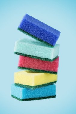Stack of kitchen multi coloured sponges on blue background. Dish washing sponges.