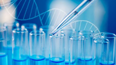 Test tubes with blue liquid water samples and pipette over blue background. Laboratory glassware, science laboratory research concept.