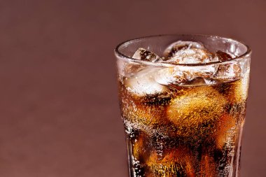 Buzlu bir bardak kola içeceğim. Kahverengi zemin üzerinde fotokopi alanı olan buzlu taze soğuk kola içeceği..