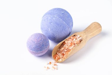 Mor banyo bombaları ve beyaz arka planda banyo deniz tuzu. Sağlıklı güzellik ürünleri. Aromaterapi ve vücut bakımı ve stres önleyici bitkisel ilaçlar.