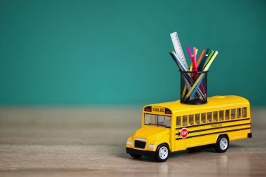 Oyuncak okul otobüsü, okul konseptine geri dönelim. Okul otobüsünün çeşitli okul malzemelerini taşıyan yaratıcı bileşimi..