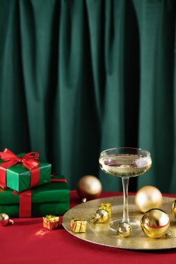 Mutlu Noeller ve mutlu yıllar. Altın Noel süsleri ve Noel hediyeleriyle bir kadeh şampanya..