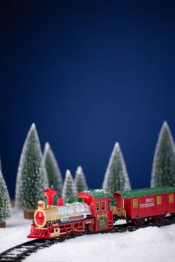 Oyuncak lokomotif, demiryolunda, Noel ağacıyla birlikte karda. Noel ve Yeni Yıl geçmişi. Yaratıcı kış Noel kompozisyonu.