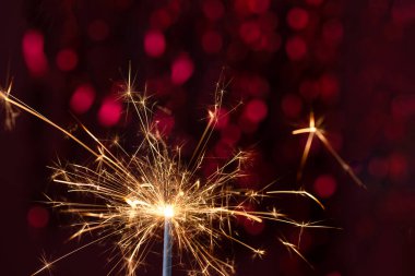 Kırmızı ışık arka planlı yanan maytap. Yeni yıl partisi geçmişi. Yeni yıl ışıldıyor.