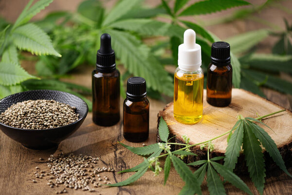 CBD конопли масло в бутылках и конопли семян с листьев конопли на деревянном фоне. Травяная альтернативная медицина.