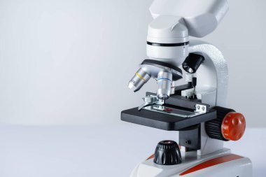 Beyaz arkaplanda fotokopi alanı olan bir mikroskop. Mikroskop altında kan örneği. HIV testi araştırması.