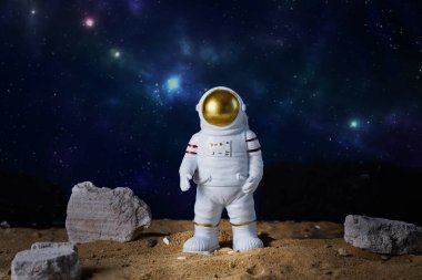Mavi yıldızlı arka planda astronot figürü, kopyalama uzayı. Astronot oyuncağı. Uzay ve uzay uçuşları konsepti. Kozmonotların Günü.