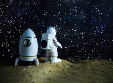 Uzaylı gezegeninde uzay mekiği olan minyatür astronot figürü, yıldızlı evrene bakıyor, bilimsel keşif kavramı ve uzay keşfi ruhu..