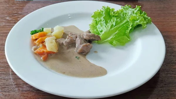 高角牛肉牛排传统的红葡萄酒 配以素食和胡萝卜土豆 放在白盘上食用 — 图库照片