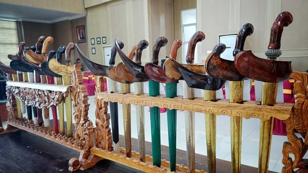 Various keris or traditional Indonesian weapons with unique wood carvings are arranged in place of weapons