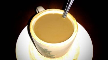 Sütlü kahve koyu arka planda bir fincanda servis edilir.