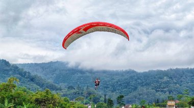 Mavi gökyüzünde uçan yamaç paraşütçüleriyle güzel dağ manzarası