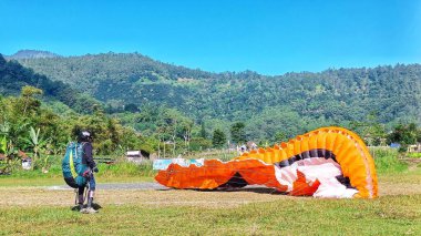 Paraşüt pilotu 8 Temmuz 2023 'te Batu City, Doğu Java, Endonezya' ya indikten sonra paraşütünü temizler.