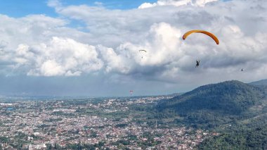 Paraglider köy manzarası ve mavi gökyüzü arkaplanı üzerinde uçuyor