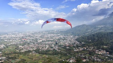 Paraglider köy manzarası ve mavi gökyüzü arkaplanı üzerinde uçuyor