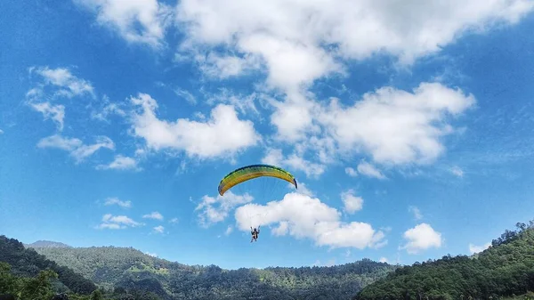 青い空と山の景色を背景にパラグライダーが高く飛ぶ — ストック写真