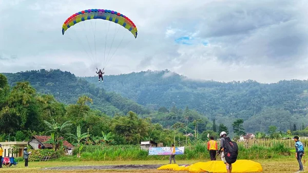 2023年7月8日にインドネシアの東ジャワ州バトゥ市で飛行した後に着陸する準備ができているパラグライダーパイロット — ストック写真