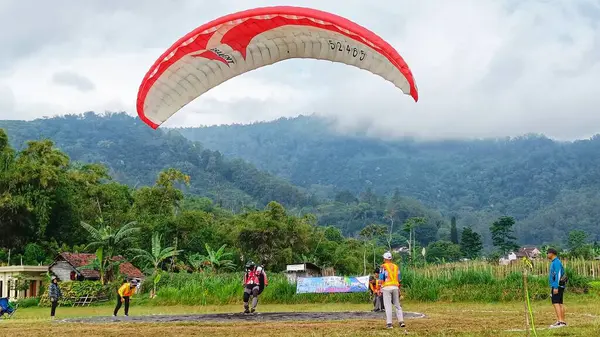 2023年7月8日にインドネシアの東ジャワ州バトゥ市で飛行した後に着陸する準備ができているパラグライダーパイロット — ストック写真