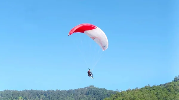 青い空と山の風景の中に高く飛ぶパラグライダー — ストック写真